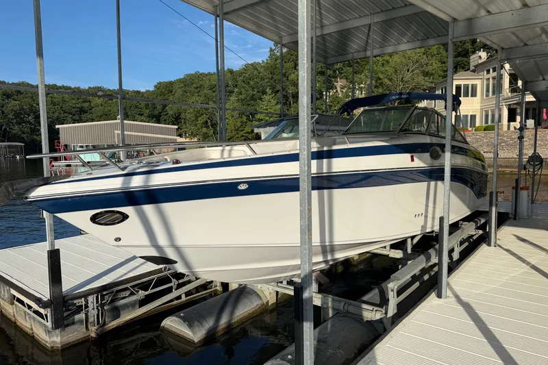 Slide: The Image of 2006 Crownline 290 CR boat docked in a marina, surrounded by lush greenery. - 1