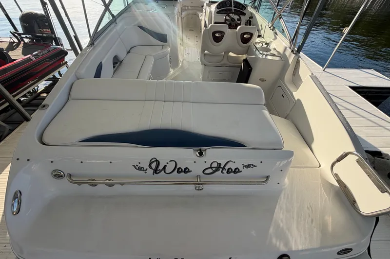 Slide: The Image of 2006 Crownline 290 CR boat interior with white seating and helm, docked by the water. - 5
