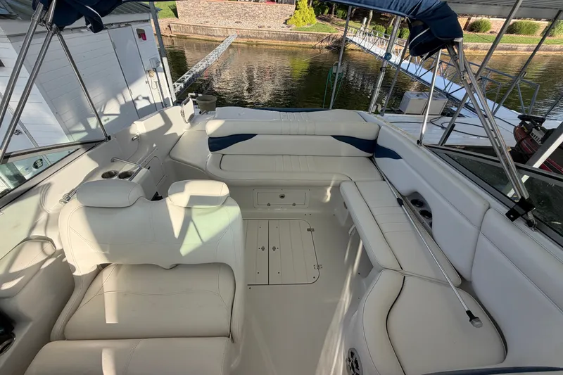 Slide: The Image of 2006 Crownline 290 CR boat interior with white seating and canopy, docked by the water. - 26