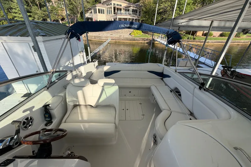 Slide: The Image of 2006 Crownline 290 CR boat interior with white seating, docked near a lakeside house. - 25