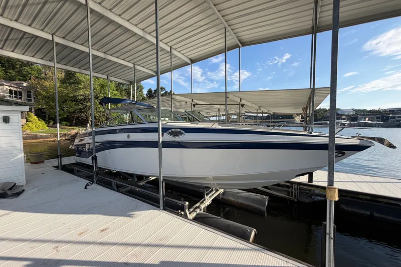 The Image of 2006 Crownline 290 CR boat docked under a covered marina on a sunny day. - 0