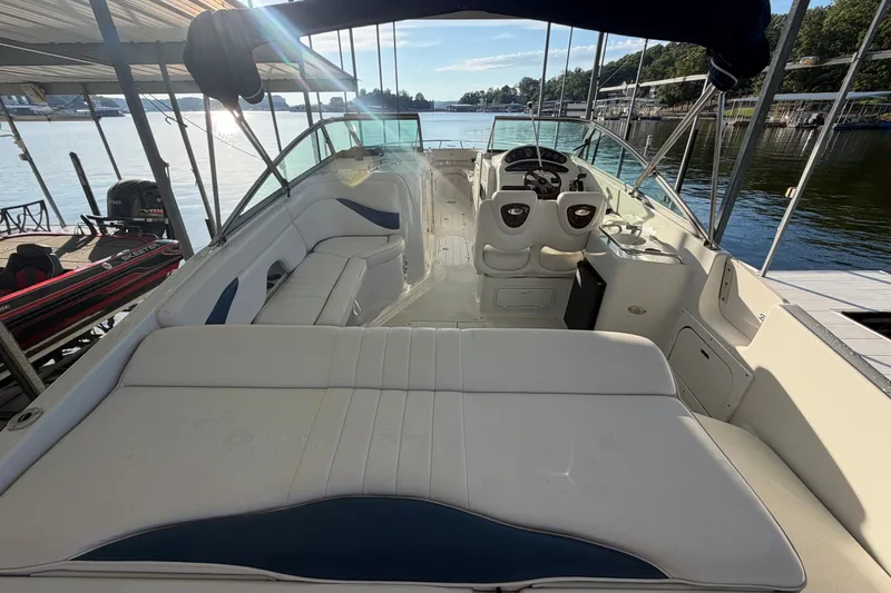 Slide: The Image of 2006 Crownline 290 CR boat interior with seating and helm, docked by a serene lake. - 6