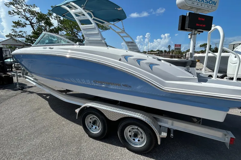 Slide: The Image of 2025 Chaparral 23 SSi OB boat on trailer, blue and white design, sunny day. - 4