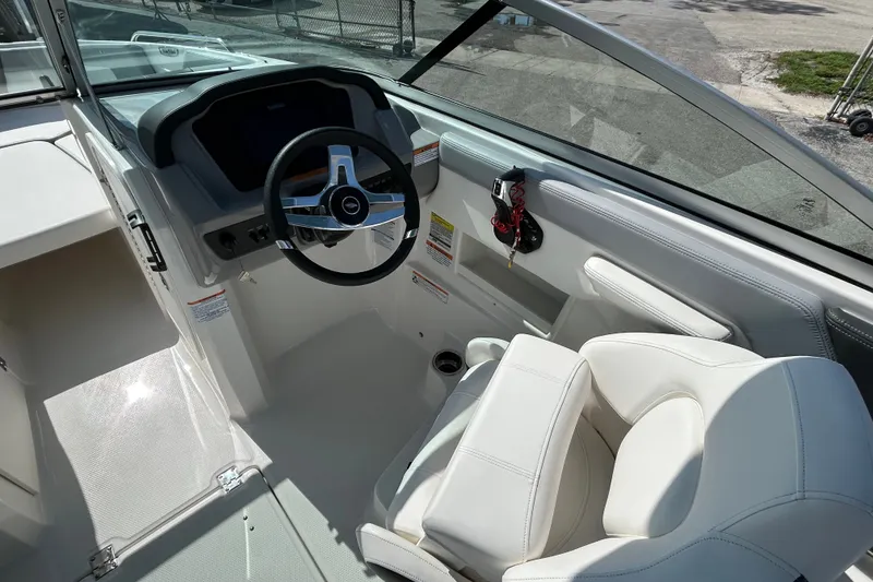 Slide: The Image of 2025 Chaparral 23 SSi OB boat cockpit with modern steering wheel and white seating. - 11