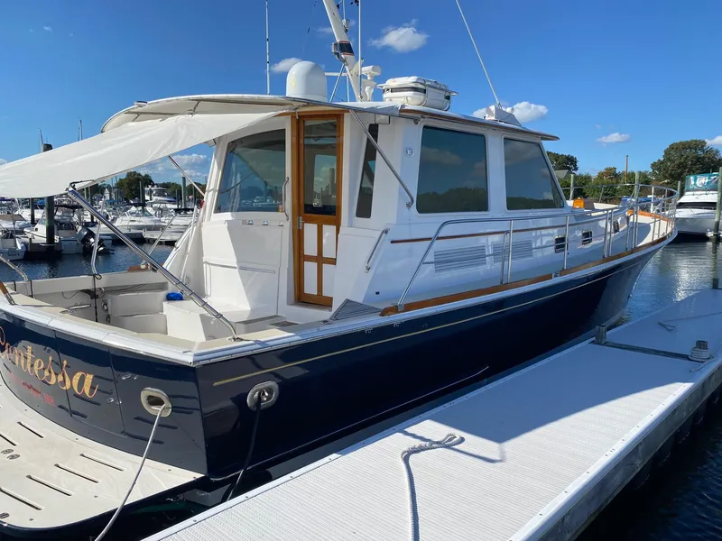 The Image of 2001 Grand Banks 49 Eastbay SX yacht docked at marina under clear blue sky. - 0
