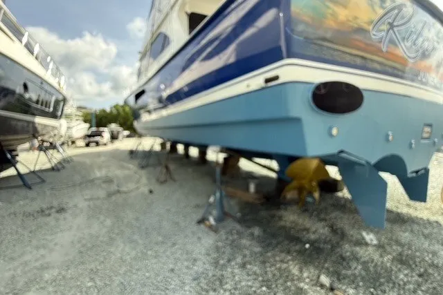 Slide: The Image of 2003 Viking 65 EB yacht on dry dock, blue hull, sunny day. - 57