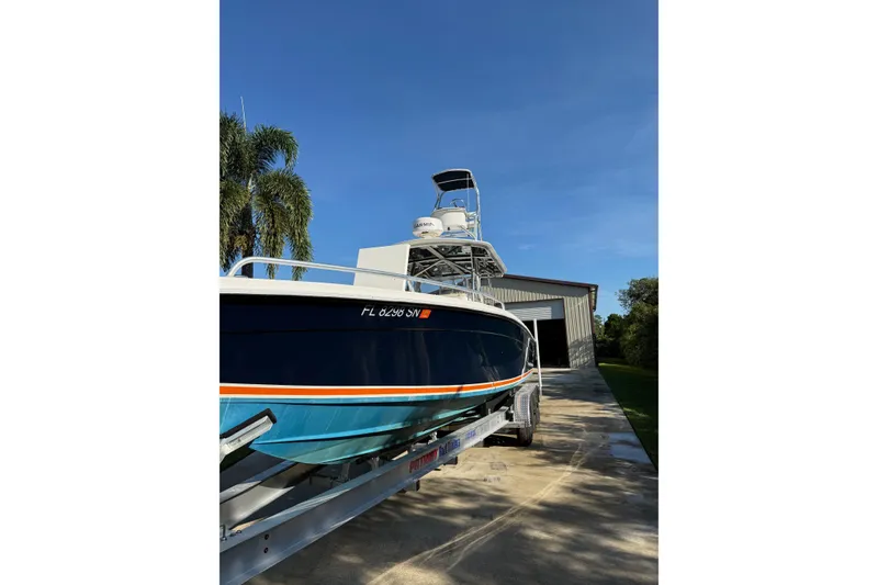 Slide: The Image of 2001 Marlago 35 Cuddy boat on trailer near a storage building, under clear blue sky. - 3