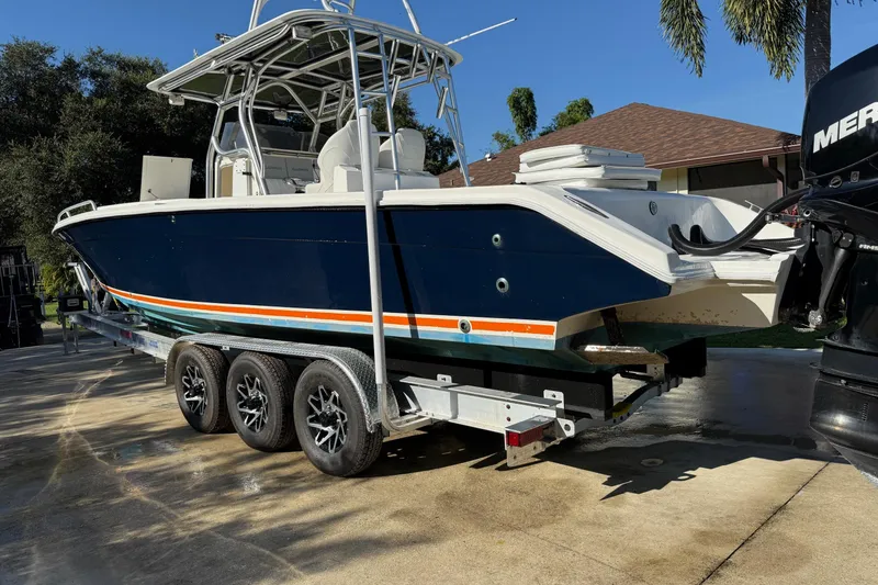 Slide: The Image of 2001 Marlago 35 Cuddy boat on trailer, blue hull, triple-axle, outdoor setting. - 19
