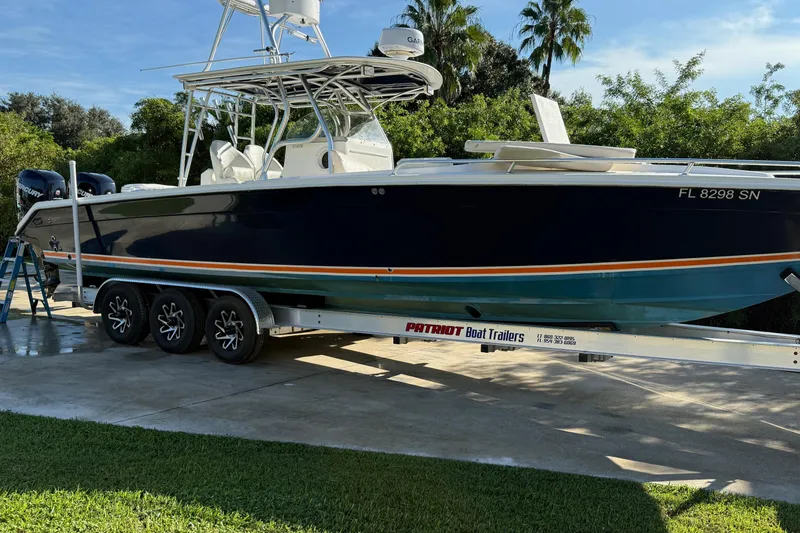 Slide: The Image of 2001 Marlago 35 Cuddy boat on trailer, parked outdoors, surrounded by greenery. - 21