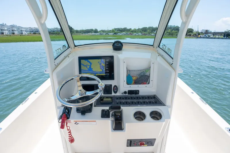 Slide: The Image of 2019 Scout 251 XSS boat helm with steering wheel and navigation display on water. - 15