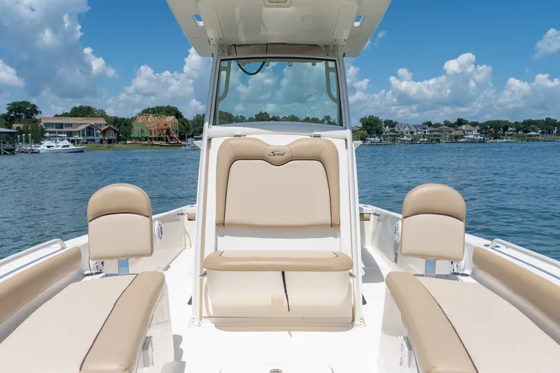 Slide: The Image of 2019 Scout 251 XSS boat interior with beige seating on a sunny day. - 19