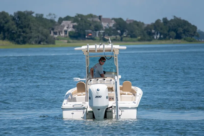 Slide: The Image of 2019 Scout 251 XSS boat cruising on a serene lake with distant houses. - 7