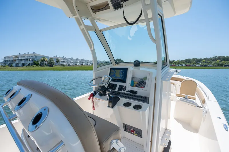 Slide: The Image of 2019 Scout 251 XSS boat interior with steering console on a sunny day. - 13