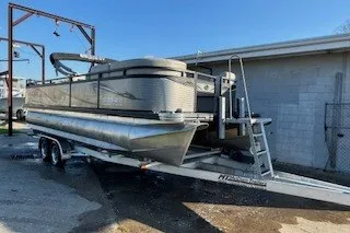 Slide: The Image of 2023 Angler Qwest 22' Pro Family Fish pontoon boat on trailer, parked outdoors. - 4