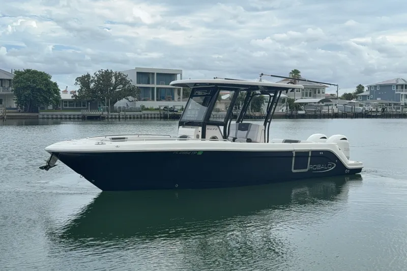 The Image of 2019 Robalo R272 Center Console boat on calm water, with modern waterfront homes in background. - 0