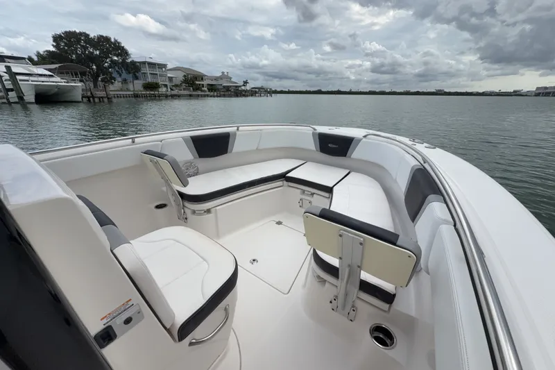 Slide: The Image of 2019 Robalo R272 Center Console boat interior with cushioned seating, docked by waterfront homes. - 20
