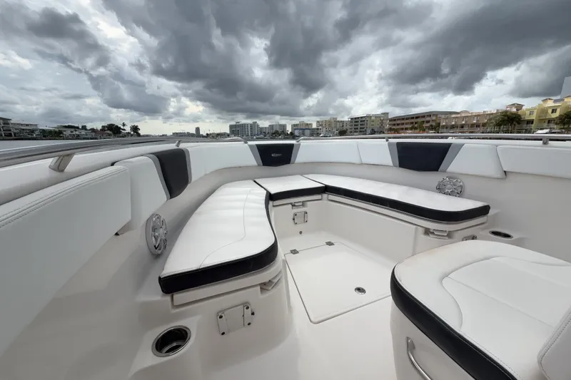 Slide: The Image of 2019 Robalo R272 Center Console boat interior with cushioned seating under cloudy skies. - 14