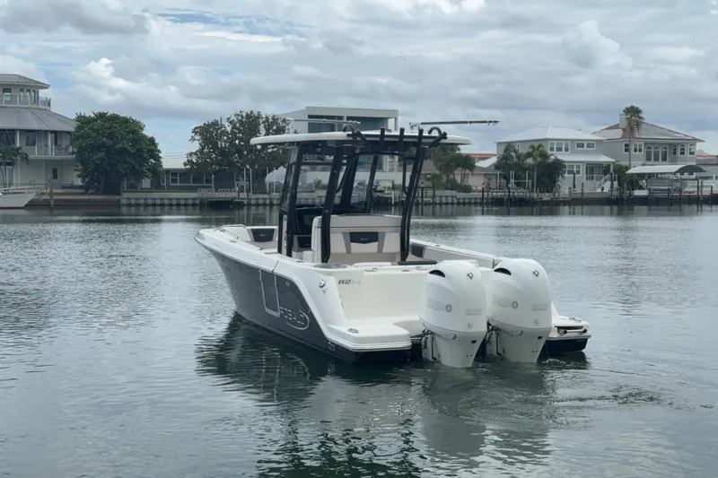 Slide: The Image of 2019 Robalo R272 Center Console boat on calm water, with dual engines and coastal homes in background. - 32