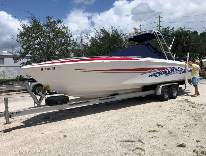 Slide: The Image of 1999 Wellcraft 302 Sport boat on a trailer, white with red and blue accents. - 1
