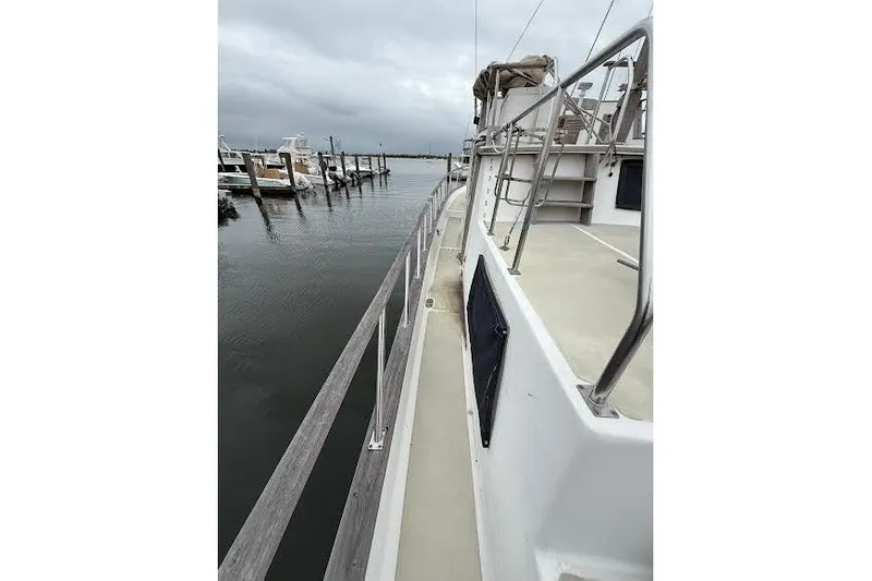 Slide: The Image of 1987 Monk 36 Trawler docked, showcasing side deck and railing under cloudy skies. - 4