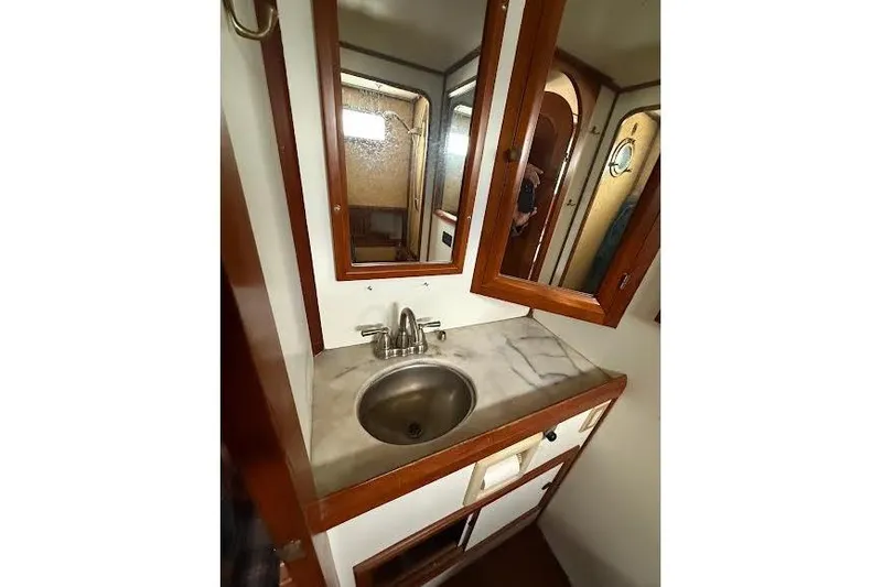 Slide: The Image of 1987 Monk 36 Trawler bathroom with sink, mirror, and wooden cabinetry. - 19