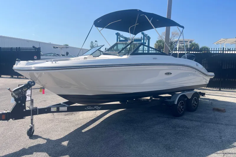 Slide: The Image of 2023 Sea Ray SPX 210 Outboard boat on trailer with canopy, parked outdoors. - 14