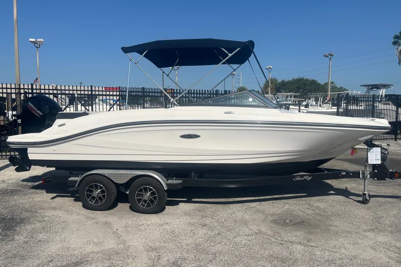 Slide: The Image of 2023 Sea Ray SPX 210 Outboard boat on trailer, with blue canopy, parked outdoors. - 11