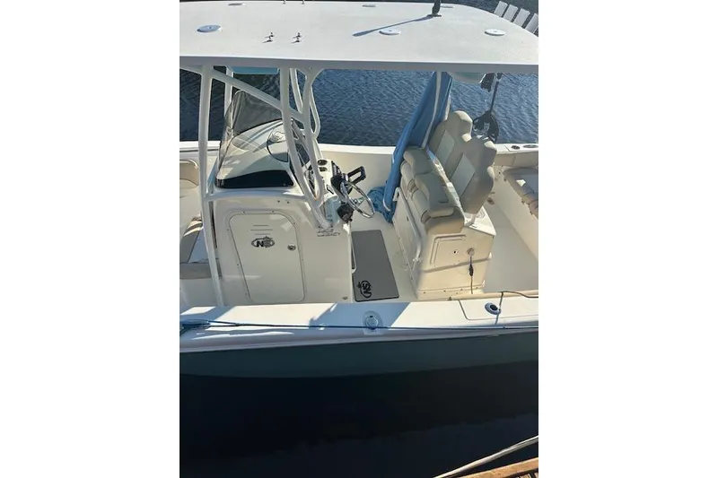 Slide: The Image of 2018 NauticStar 2602 Legacy boat interior with seating and helm, docked on water. - 41