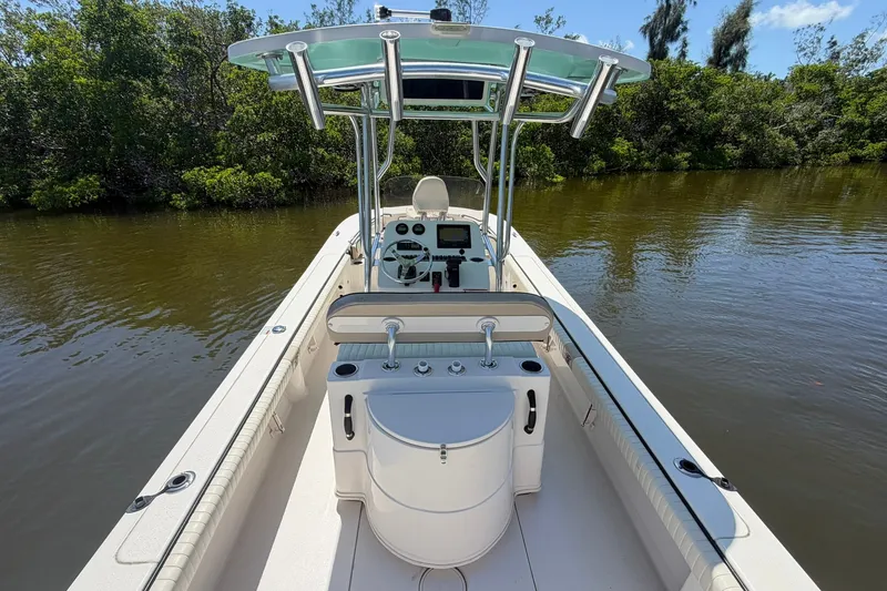 Slide: The Image of 2022 Carolina Skiff 26 Ultra Elite boat on calm water, surrounded by lush greenery. - 14