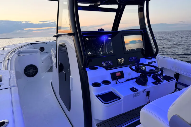 Slide: The Image of 2027 Tidewater 330 CC Adventure boat cockpit at sunset, featuring advanced navigation displays. - 27