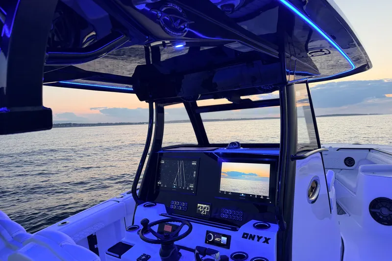 Slide: The Image of 2027 Tidewater 330 CC Adventure boat interior with illuminated dashboard at sunset on the water. - 21