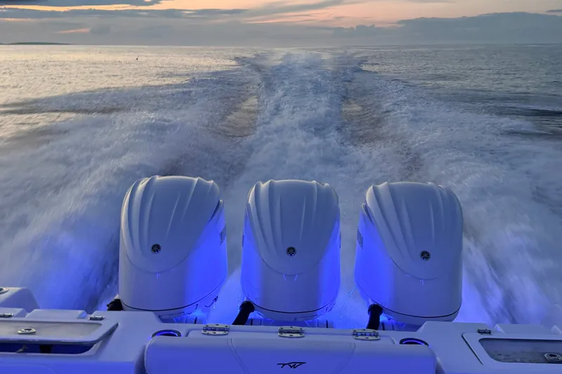 Slide: The Image of Three powerful outboard engines propel a boat at sunset, gliding across the water. - 10