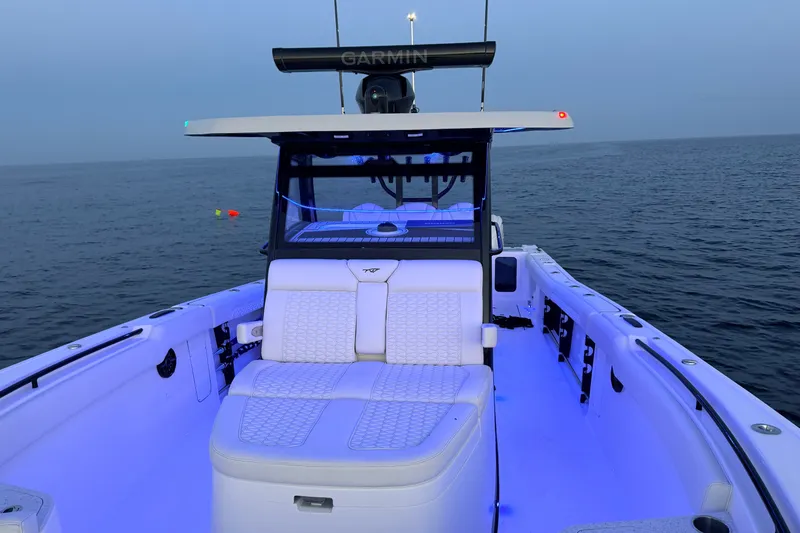 Slide: The Image of 2027 Tidewater 330 CC Adventure boat with illuminated seating on calm ocean waters. - 17