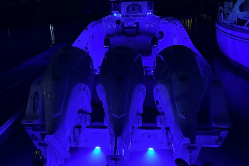 Slide: The Image of A boat with three engines illuminated in blue light, docked at night. - 13