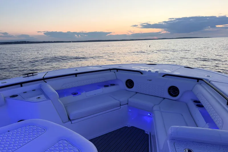 Slide: The Image of 2027 Tidewater 330 CC Adventure boat interior at sunset, featuring blue LED lighting. - 7