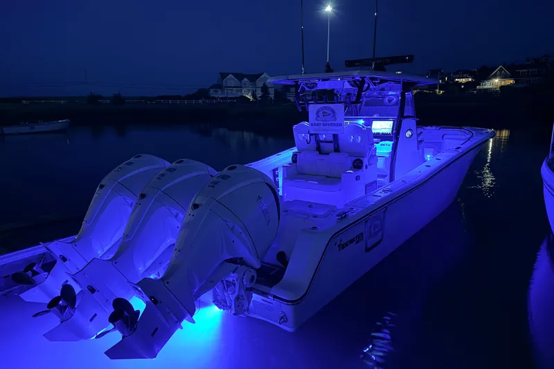 Slide: The Image of 2027 Tidewater 330 CC Adventure boat illuminated at night with blue LED lights. - 15