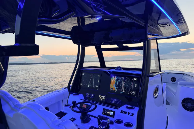 Slide: The Image of 2027 Tidewater 330 CC Adventure boat interior with illuminated dashboard at sunset. - 4