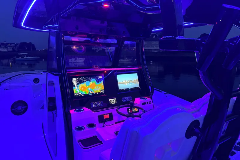 Slide: The Image of 2027 Tidewater 330 CC Adventure boat cockpit with illuminated navigation screens at night. - 14