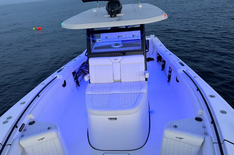 Slide: The Image of 2027 Tidewater 330 CC Adventure boat with illuminated seating on calm ocean waters. - 20
