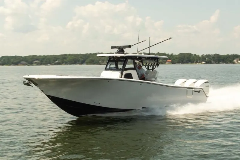 Slide: The Image of Manufacturer Provided Image: 2027 Tidewater 330 CC Adventure boat cruising on a lake under a clear sky. - 2
