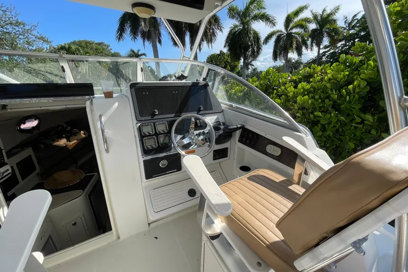 Slide: The Image of 2001 Hydra-Sports Vector 2800 WA boat cockpit with steering wheel and seating, surrounded by lush greenery. - 31
