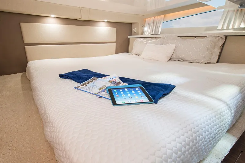 Slide: The Image of Manufacturer Provided Image: Luxurious cabin interior of 2026 Regal 33 XO yacht with tablet and magazines on bed. - 17