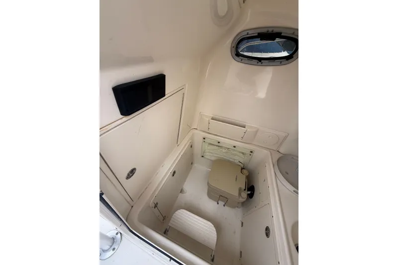 Slide: The Image of Interior cabin of 2005 Boston Whaler 270 Outrage, featuring compact storage and a small window. - 18