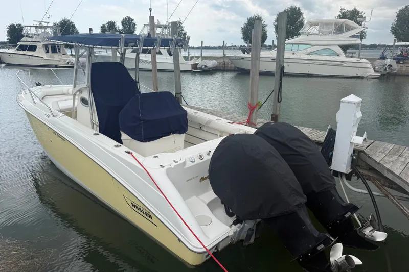 Slide: The Image of 2005 Boston Whaler 270 Outrage docked, featuring dual engines and a covered seating area. - 1