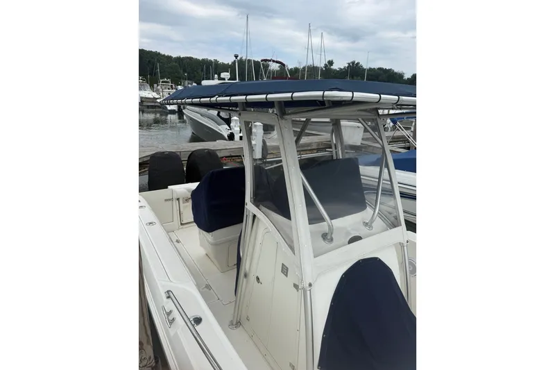Slide: The Image of 2005 Boston Whaler 270 Outrage boat docked at marina, featuring blue canopy and seating. - 5