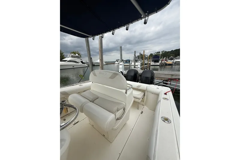 Slide: The Image of 2005 Boston Whaler 270 Outrage boat interior at marina, featuring seating and dual engines. - 15