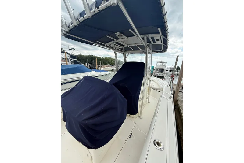 Slide: The Image of 2005 Boston Whaler 270 Outrage boat with covered seating and canopy at a marina. - 6