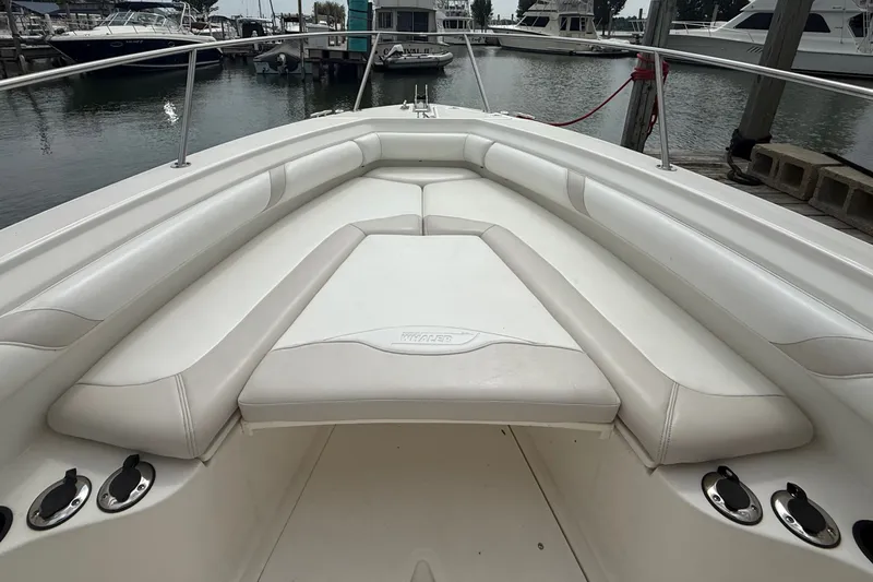 Slide: The Image of 2005 Boston Whaler 270 Outrage boat interior with white cushioned seating at marina. - 12
