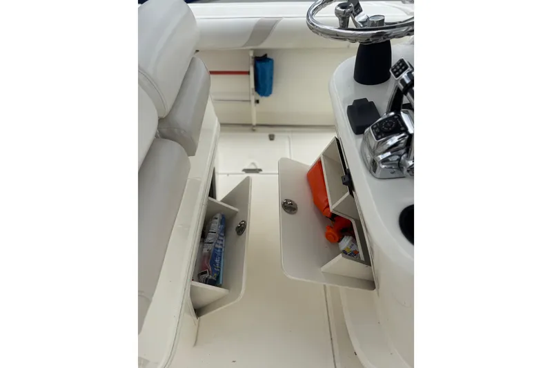 Slide: The Image of 2005 Boston Whaler 270 Outrage helm with open storage compartments and steering wheel. - 14