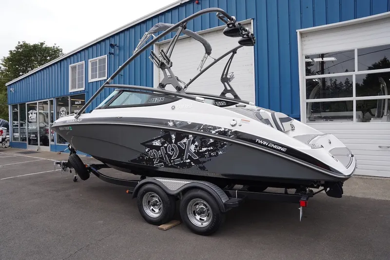 Slide: The Image of 2014 Yamaha Boats 212X on trailer, parked outside a blue building. - 1